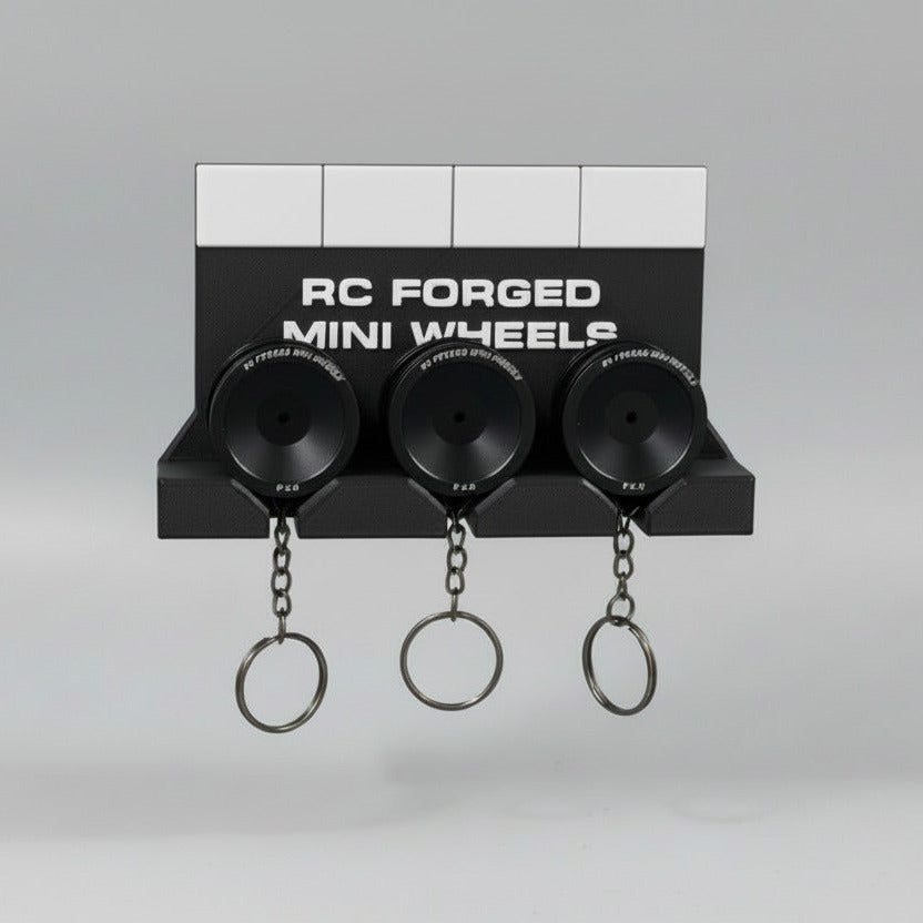 A 3D printed wall key holder with a black base and three key chains attached to mini wheels. The wheels are black, and the key holder features colored sections (red, yellow, green) on the wall mount.