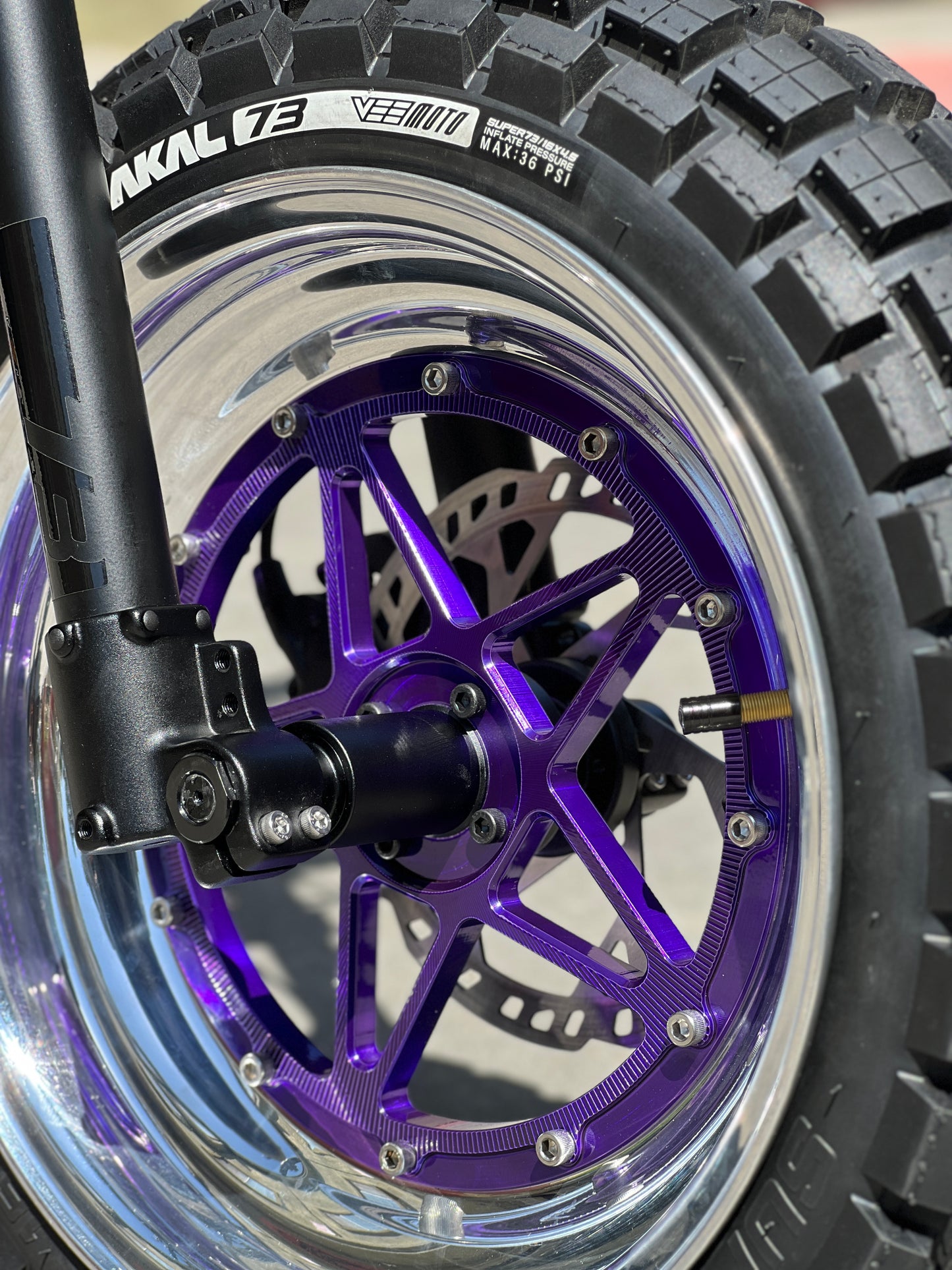 Close-up of a motorcycle wheel with a purple rim and 'Nakl 73' branding.