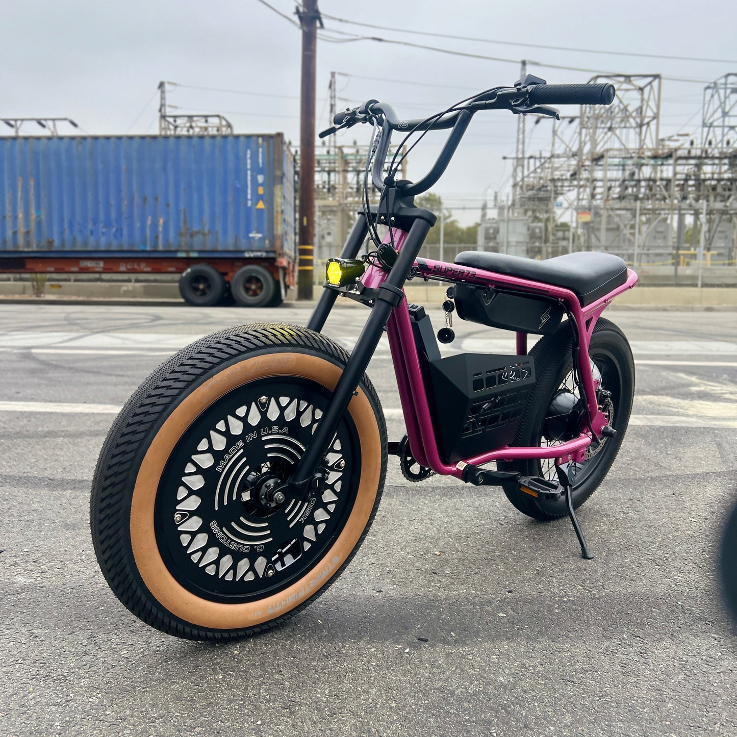 Black and pink electric bike on a road with industrial background