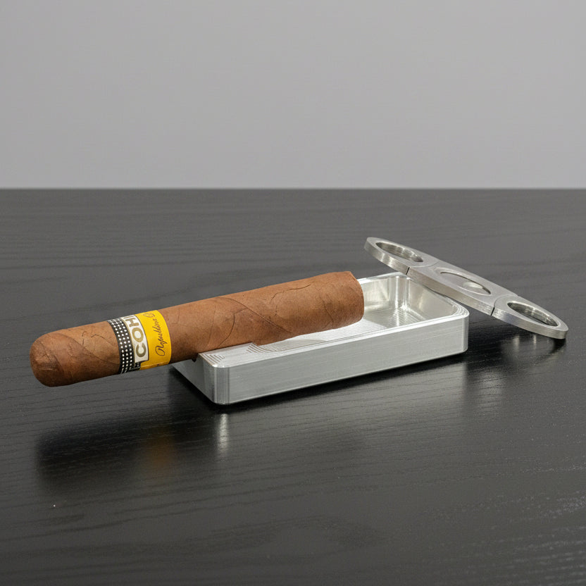 Cigar with a cutter and ashtray on a dark surface