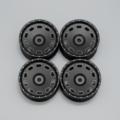 A set of four black anodized finish 1/10 scale drift wheels with a 12 mm hex size, displayed on a wooden surface.