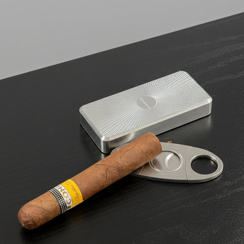 Cigar with a cutter and metallic box on a dark surface