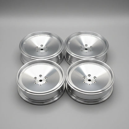 Four silver aluminum RC forged Mini Wheels displayed on a gray concrete floor.