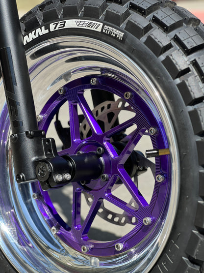 Close-up of a motorcycle wheel with a purple rim and 'Nakl 73' branding.