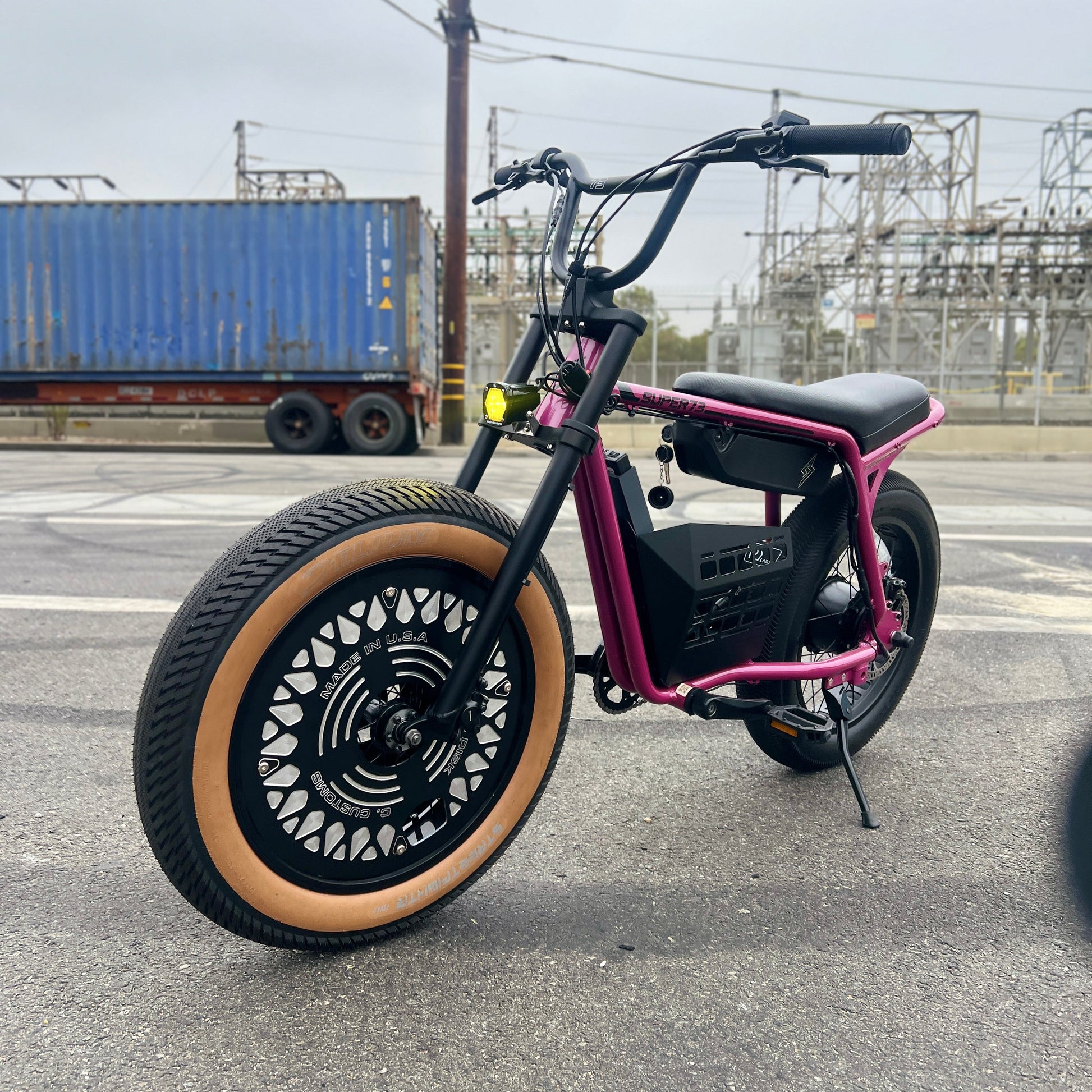 Black and pink electric bike on a road with industrial background