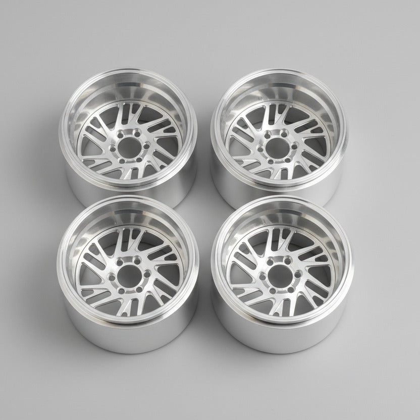 Four silver alloy wheels on a wooden surface