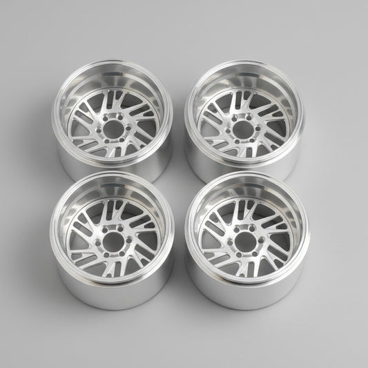 Four silver alloy wheels on a wooden surface