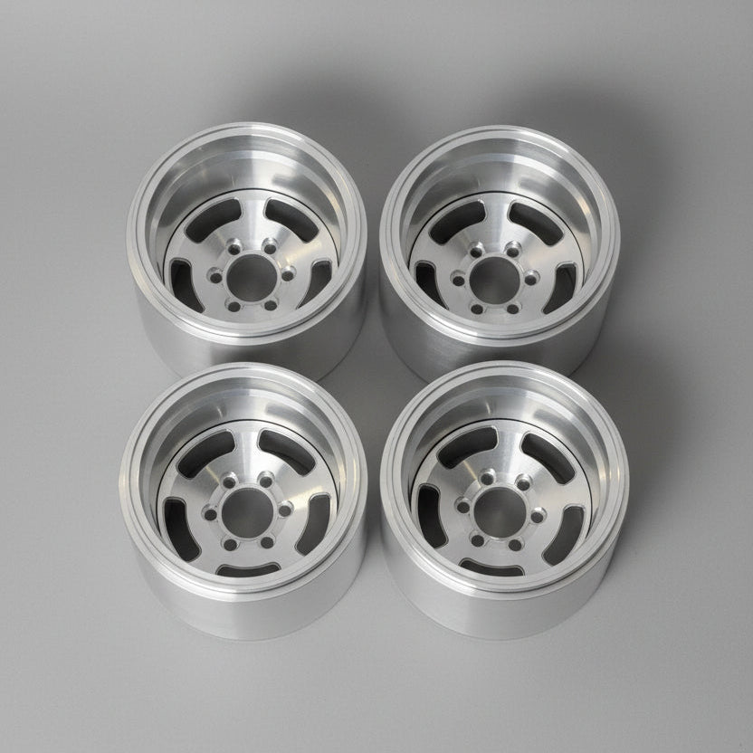 Four polished silver aluminum wheel rims arranged in a 2x2 grid on a gray concrete floor.
