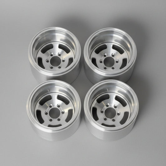 Four polished silver aluminum wheel rims arranged in a 2x2 grid on a gray concrete floor.