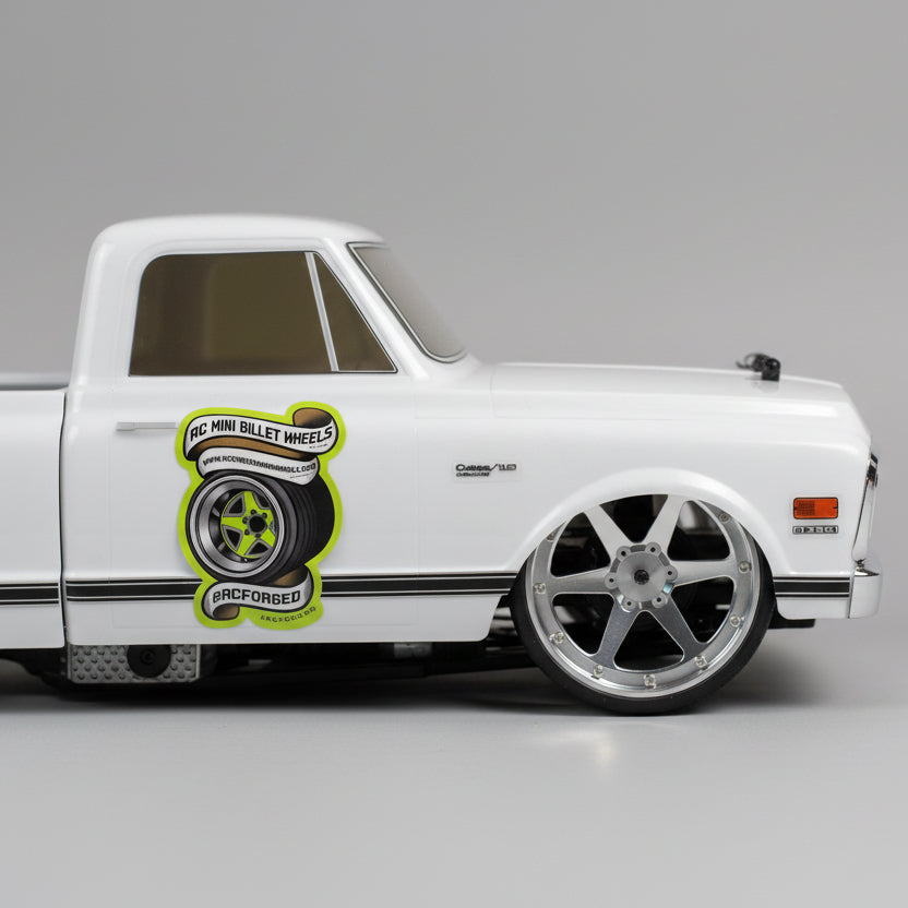 Model car with a wheel on a wooden surface, with tools in the background rcforged 