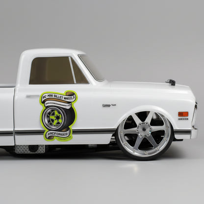 Model car with a wheel on a wooden surface, with tools in the background rcforged 