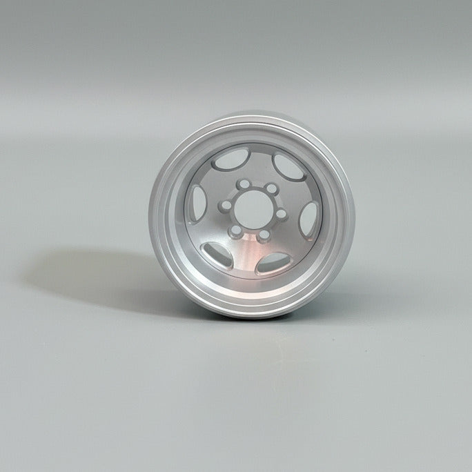 A single silver aluminum RC car wheel with a six bolt pattern hub, held in a hand wearing a green glove.