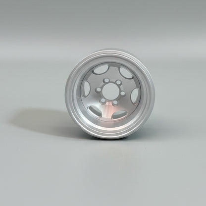 A single silver aluminum RC car wheel with a six bolt pattern hub, held in a hand wearing a green glove.