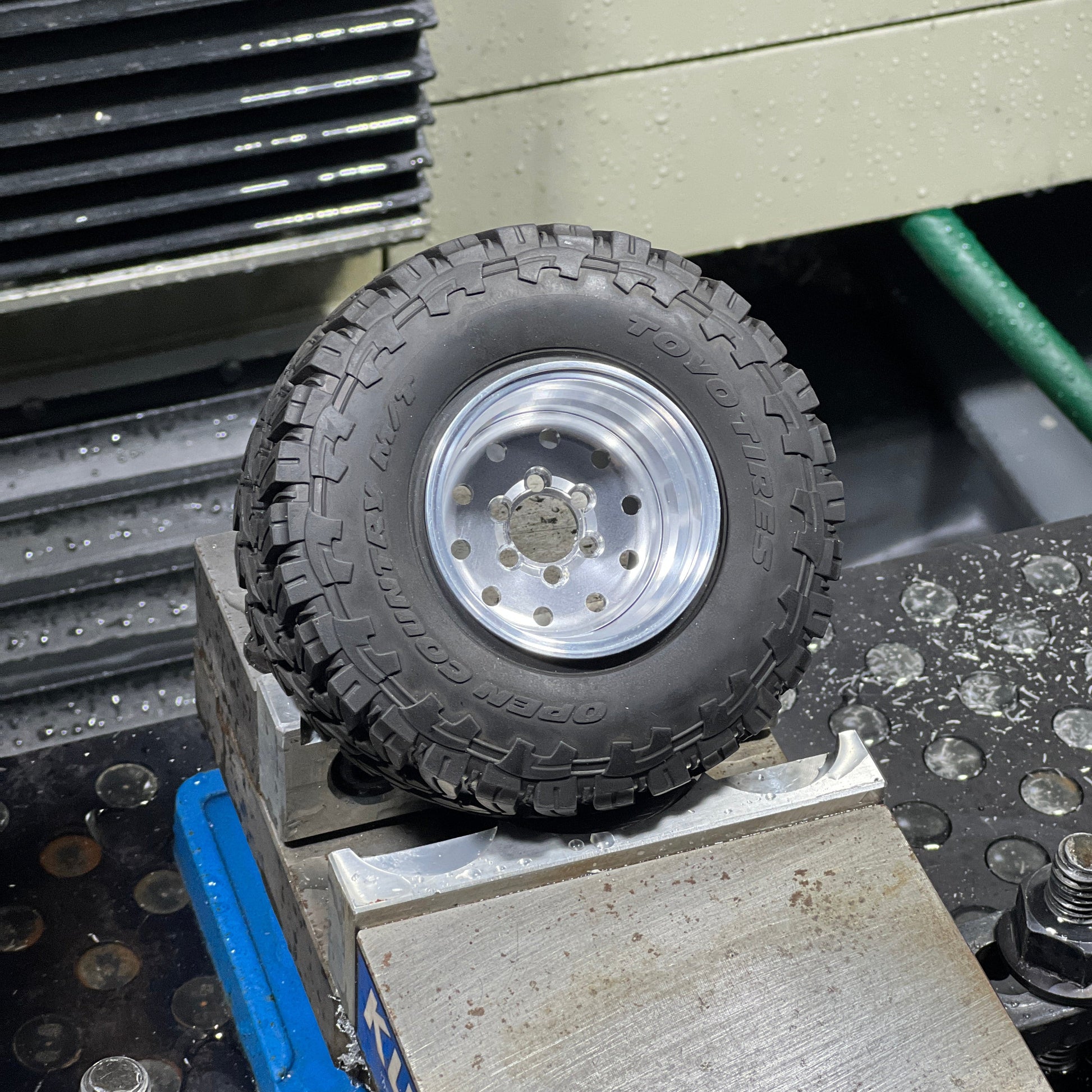 Close-up of a tire on a metal surface with tools and equipment in the background