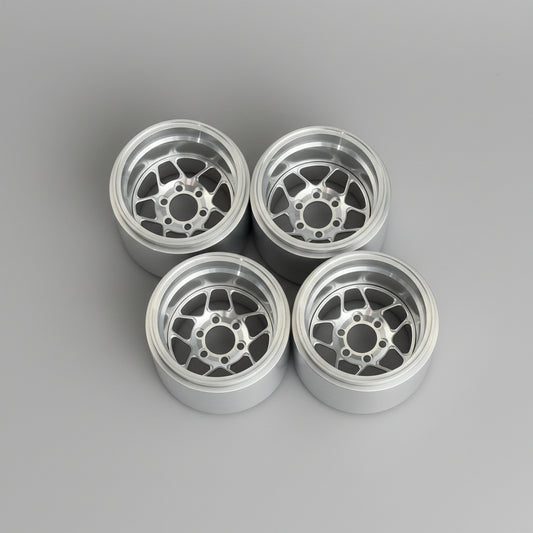 Four silver multi-spoke alloy wheels arranged in a 2x2 grid on a textured gray concrete floor.