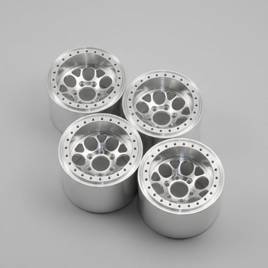 Four silver metallic multi-spoke wheels with a complex multi-hole center design, arranged on a gray concrete floor.