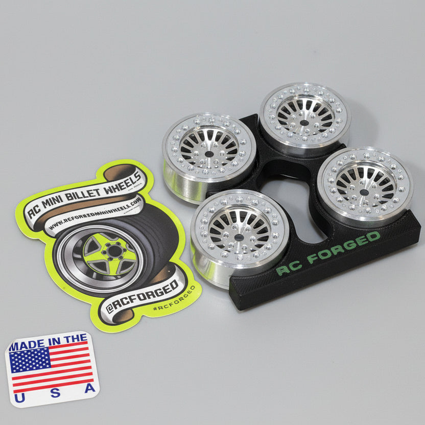 A set of four aluminum scale wheels for remote control vehicles, with bead locks and hardware, displayed on a wooden surface.