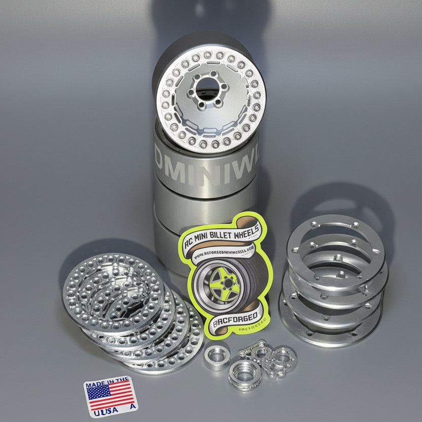 A set of beadlock wheels for remote control trucks, displayed on a wooden surface, with various components like screws and bead lock rings visible.