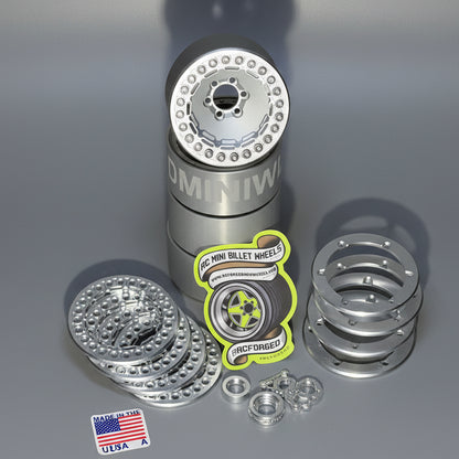 A set of beadlock wheels for remote control trucks, displayed on a wooden surface, with various components like screws and bead lock rings visible.