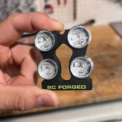 Hand holding a set of RCFORGED car wheels with a blurred workshop background