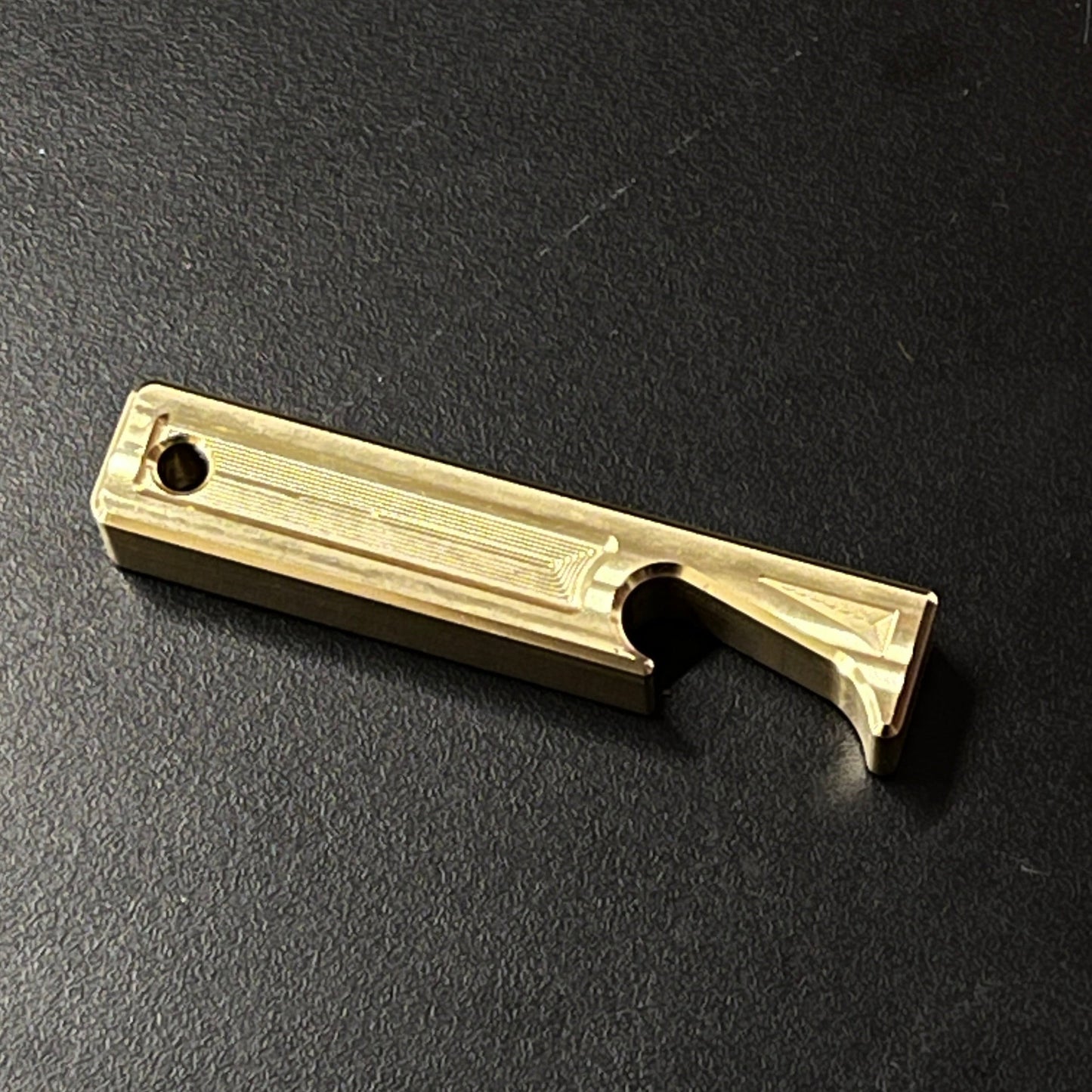 Brass bottle opener on a black surface